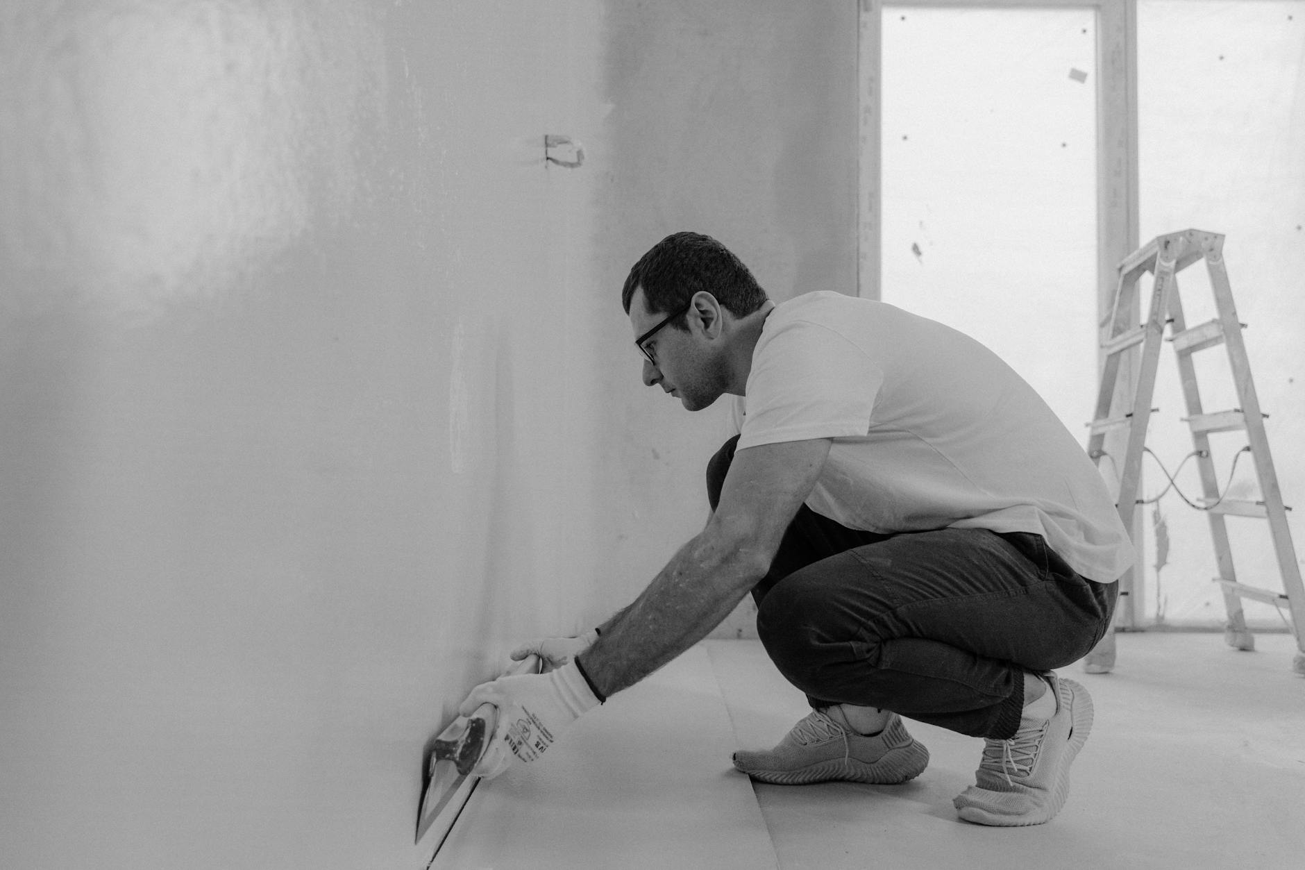 grayscale photo of a man painting a house