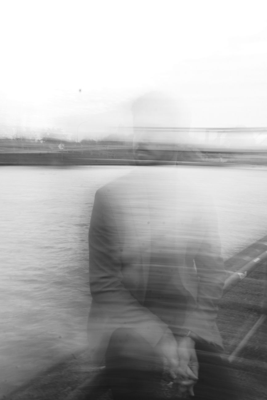 blurred photo of a man sitting on a bridge