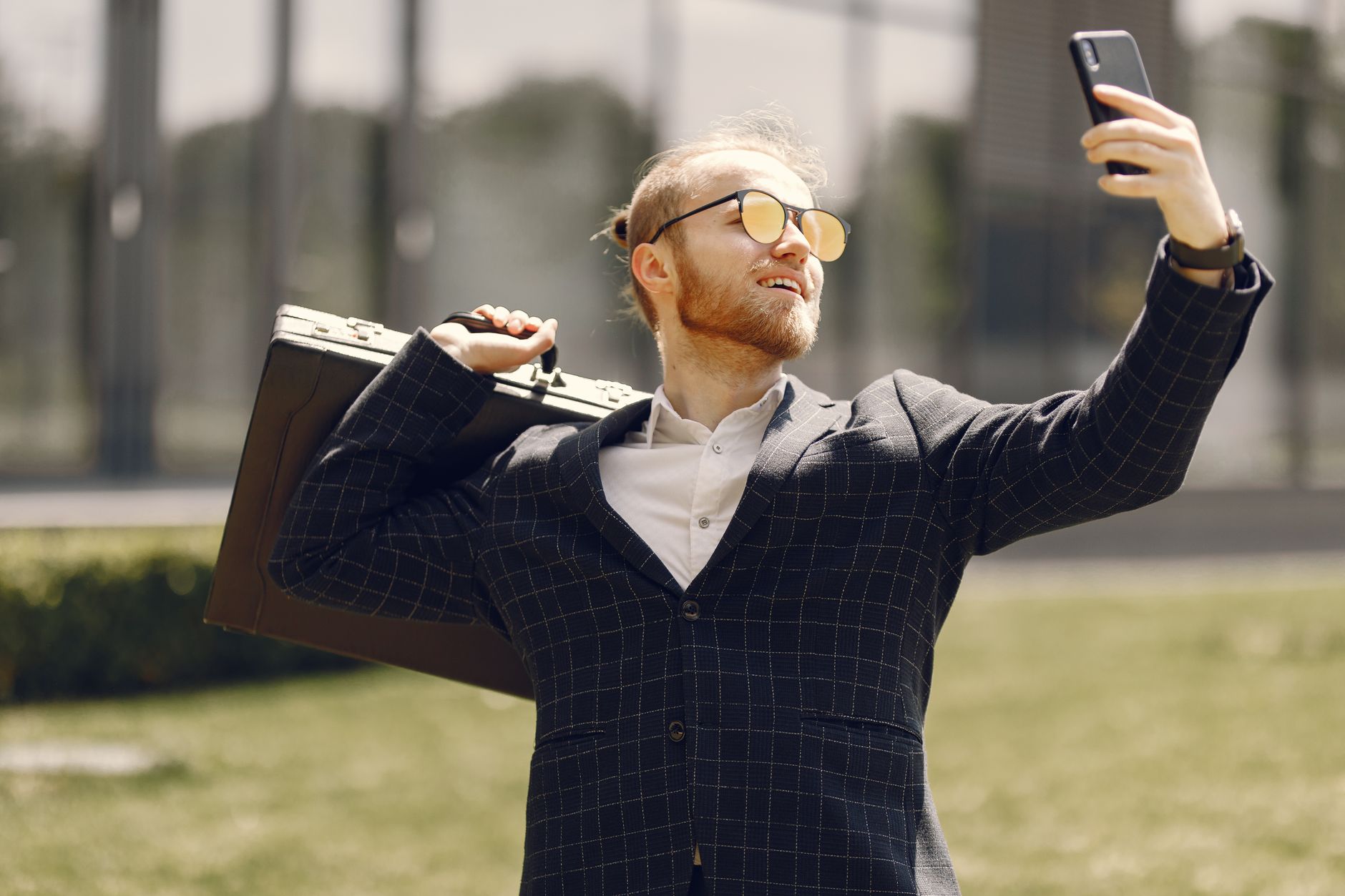 a bearded man holding a briefcase while taking a selfie