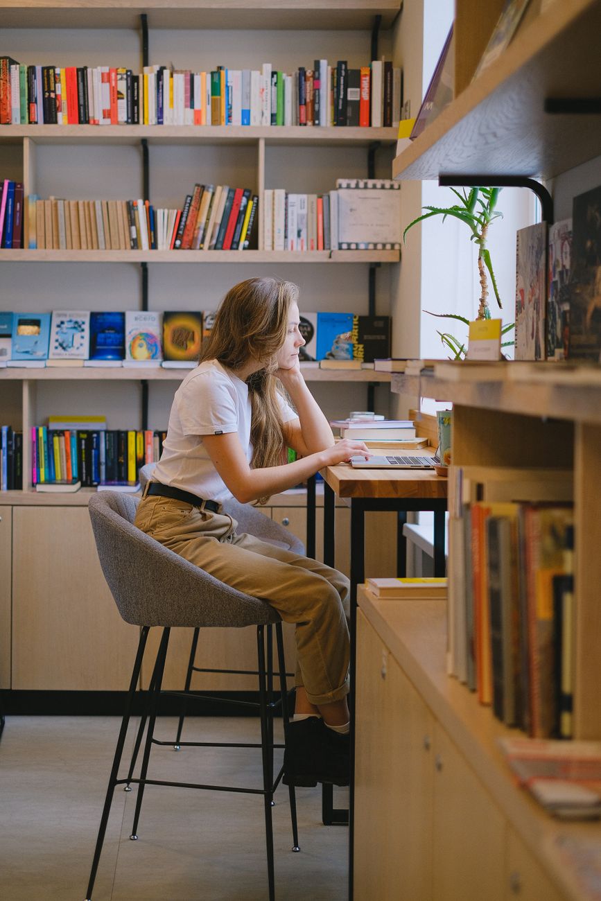 woman sitting on gray bar stool while studying in the library