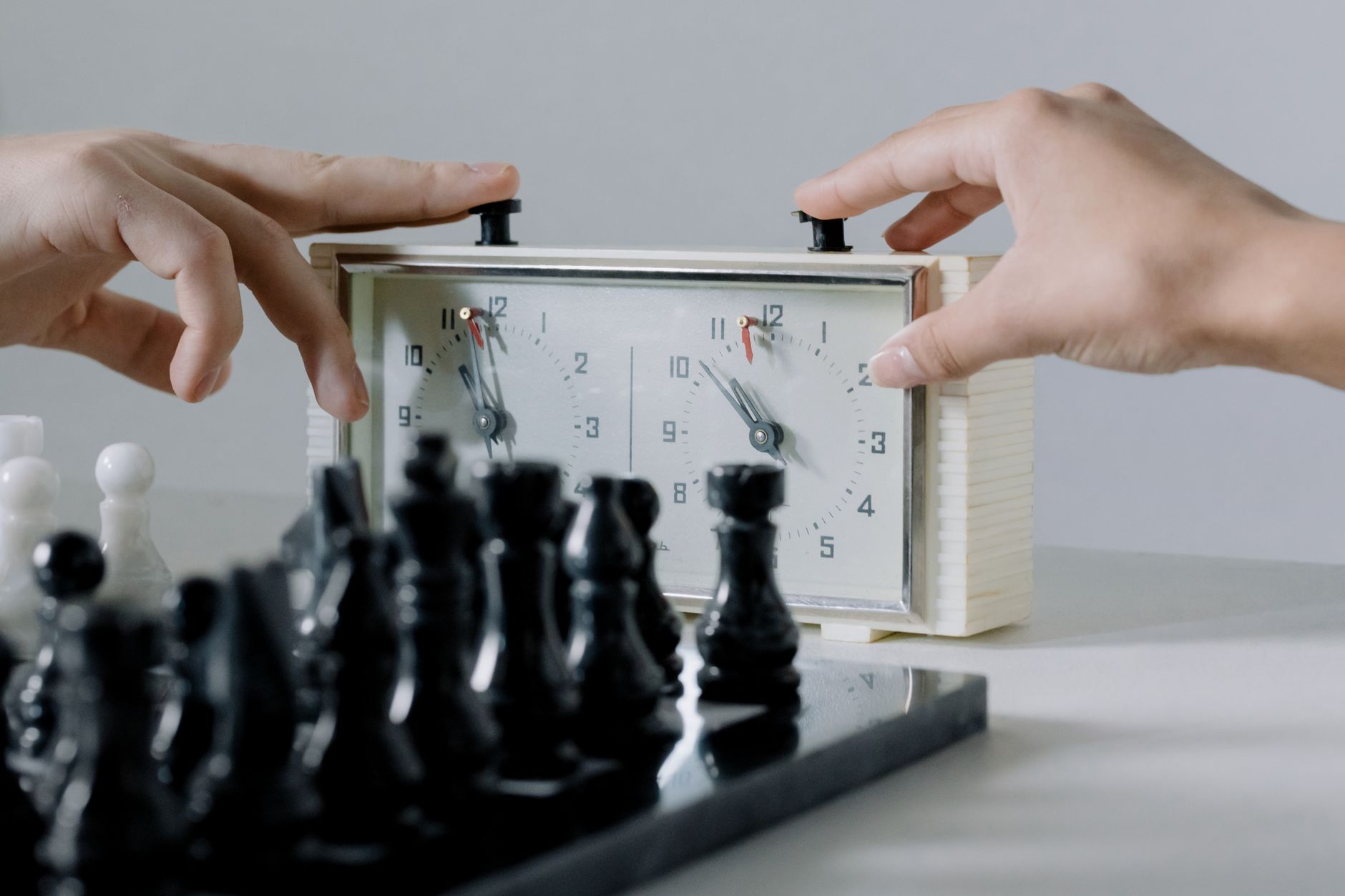 hands pressing the button of a clock near chessboard
