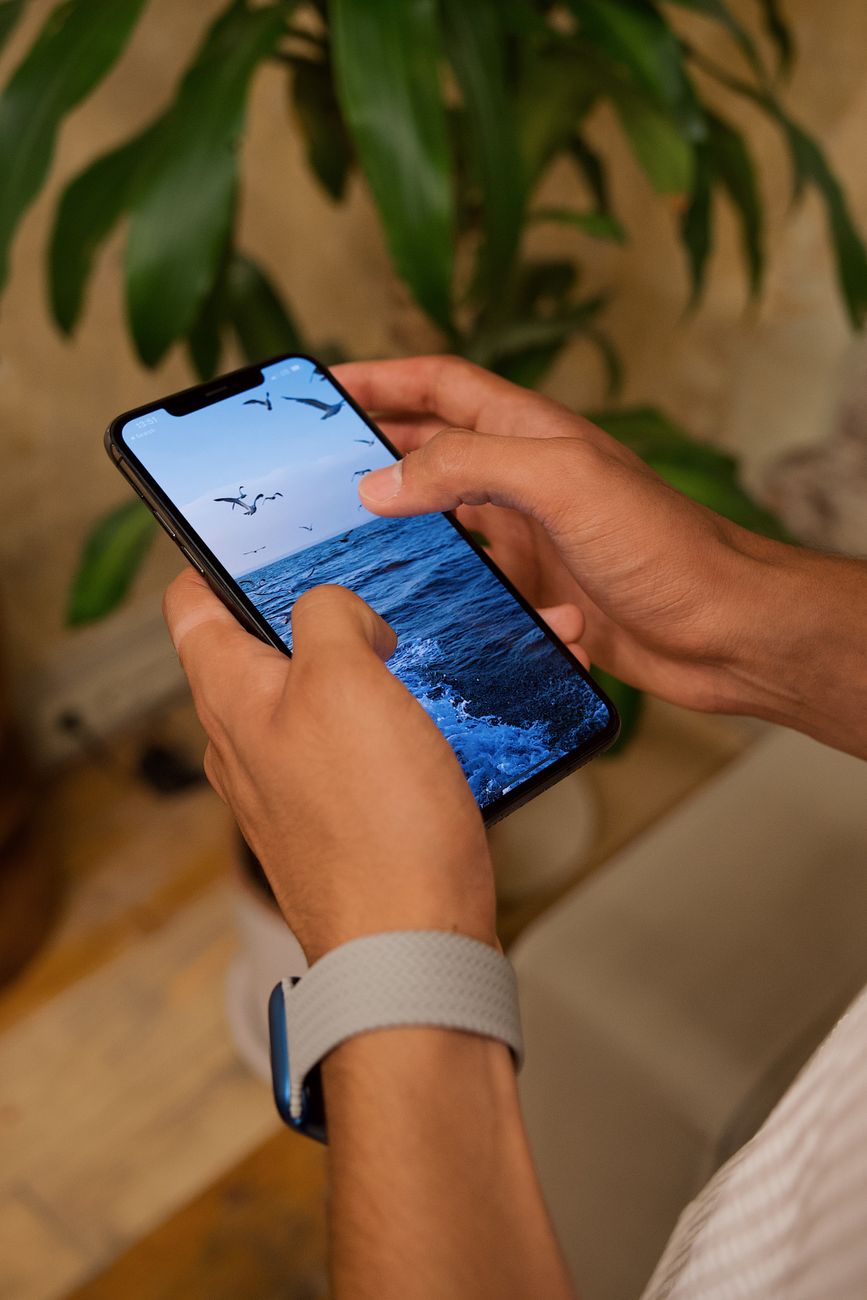 man looking at photo of sea on smartphone