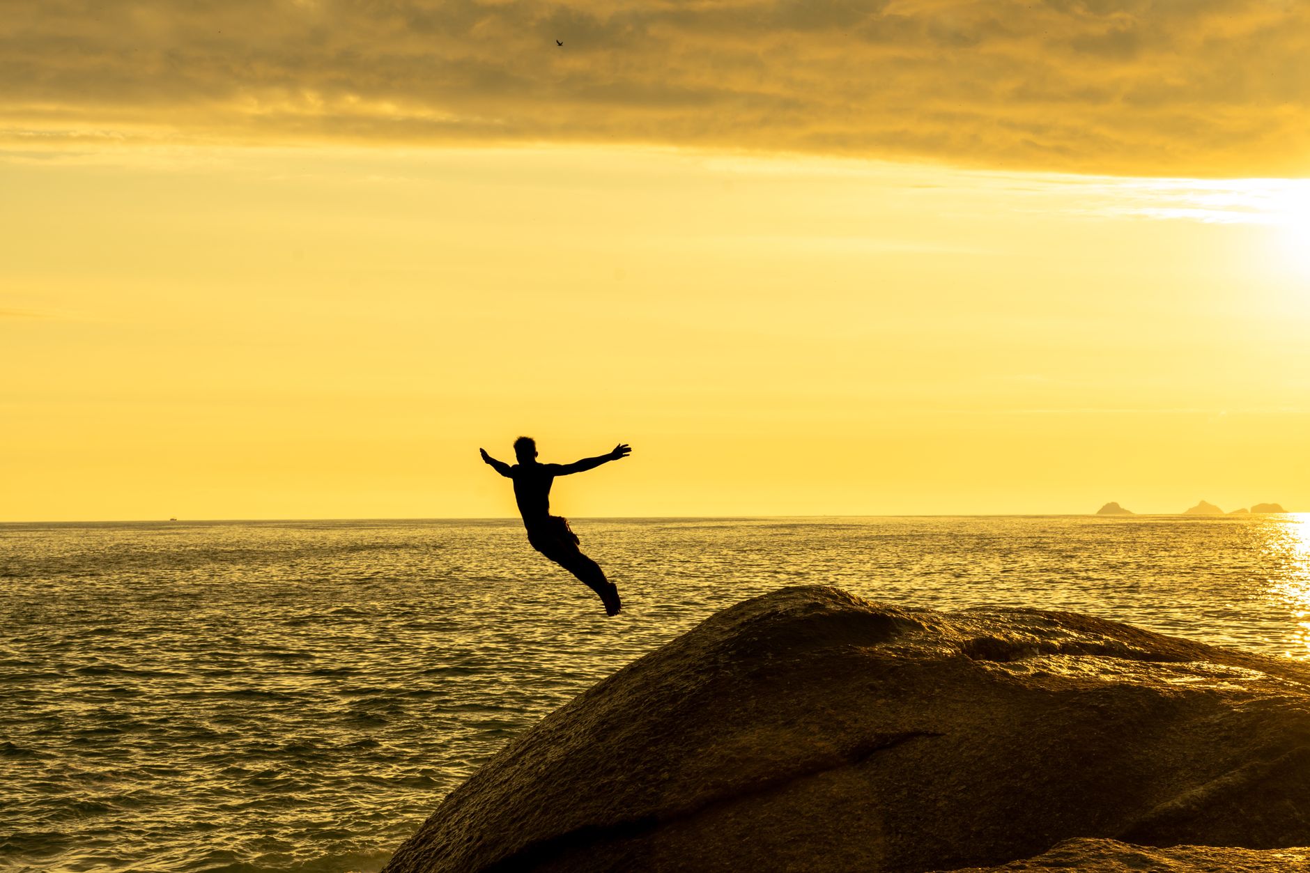 man jumping to sea at golden hour