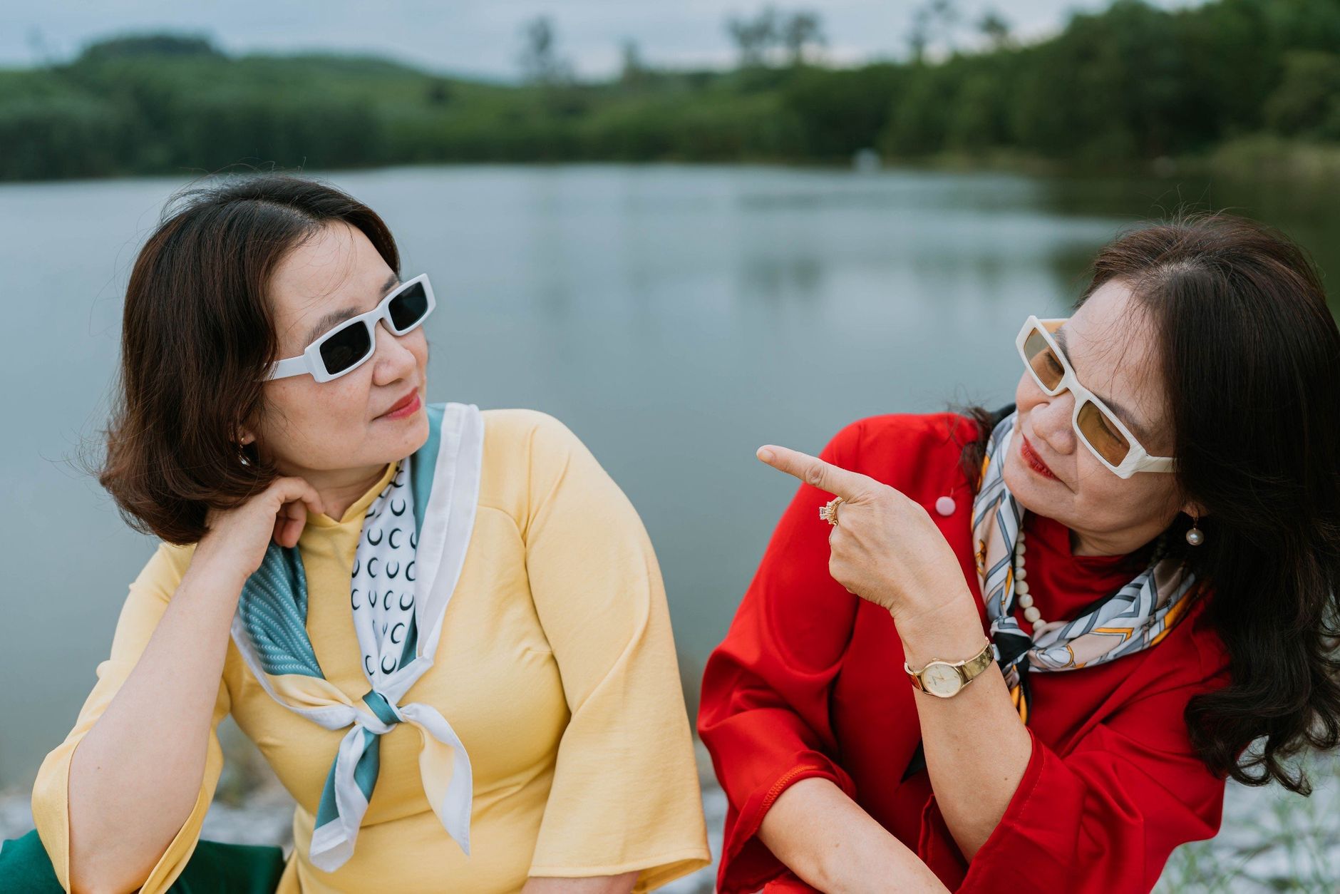 women talking while sitting on the riverbank