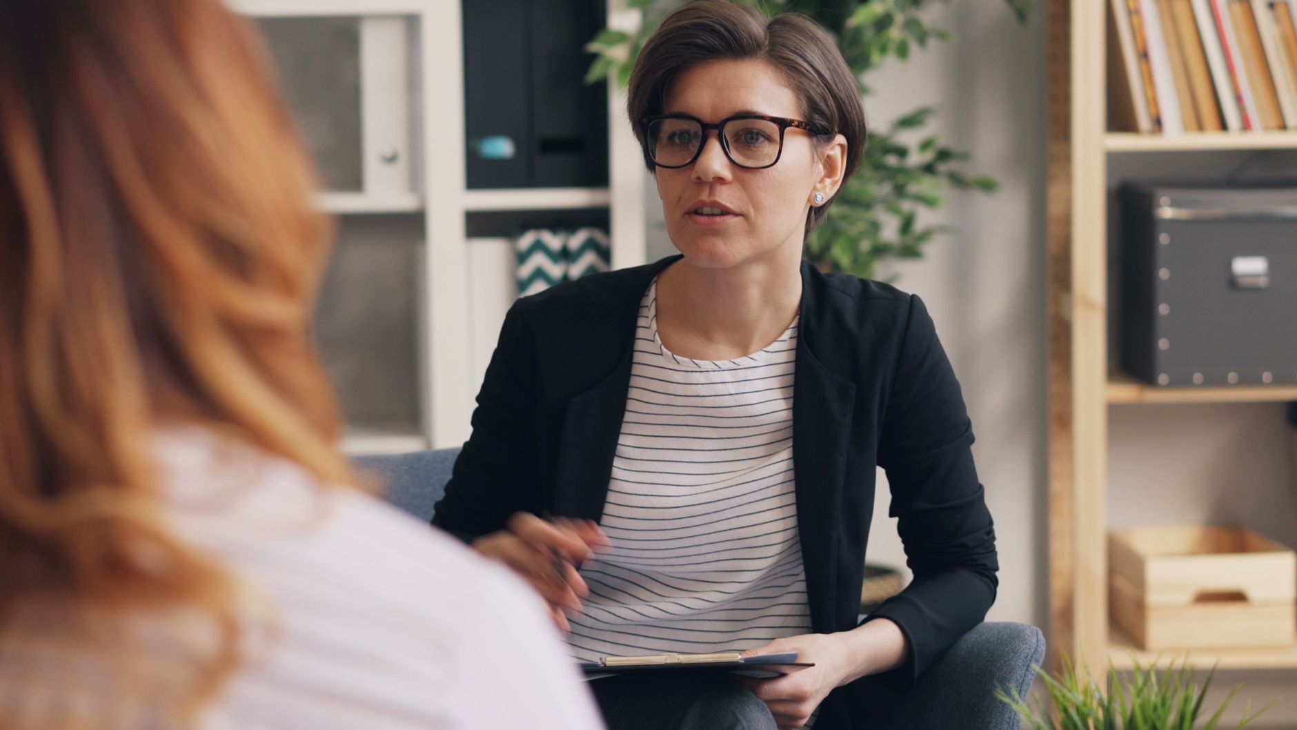 a woman sitting in a chair talking to another woman