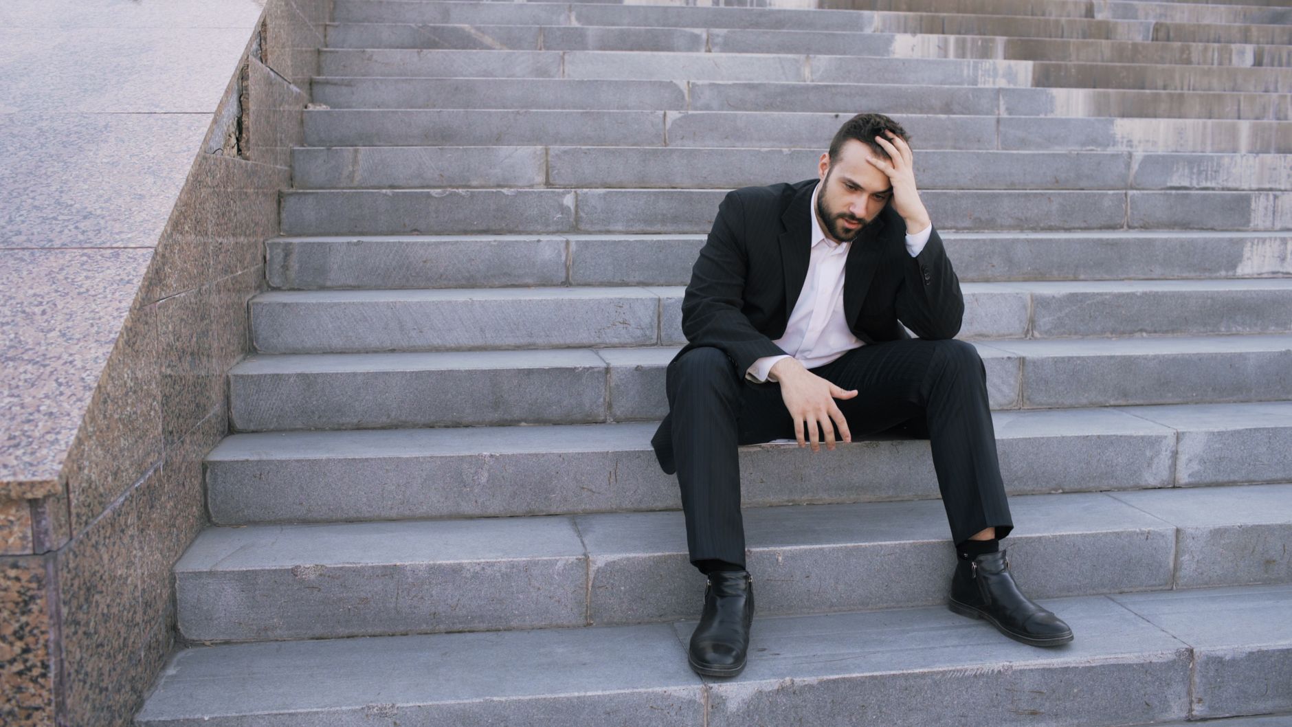 stressed businessman sitting on stairs outdoors