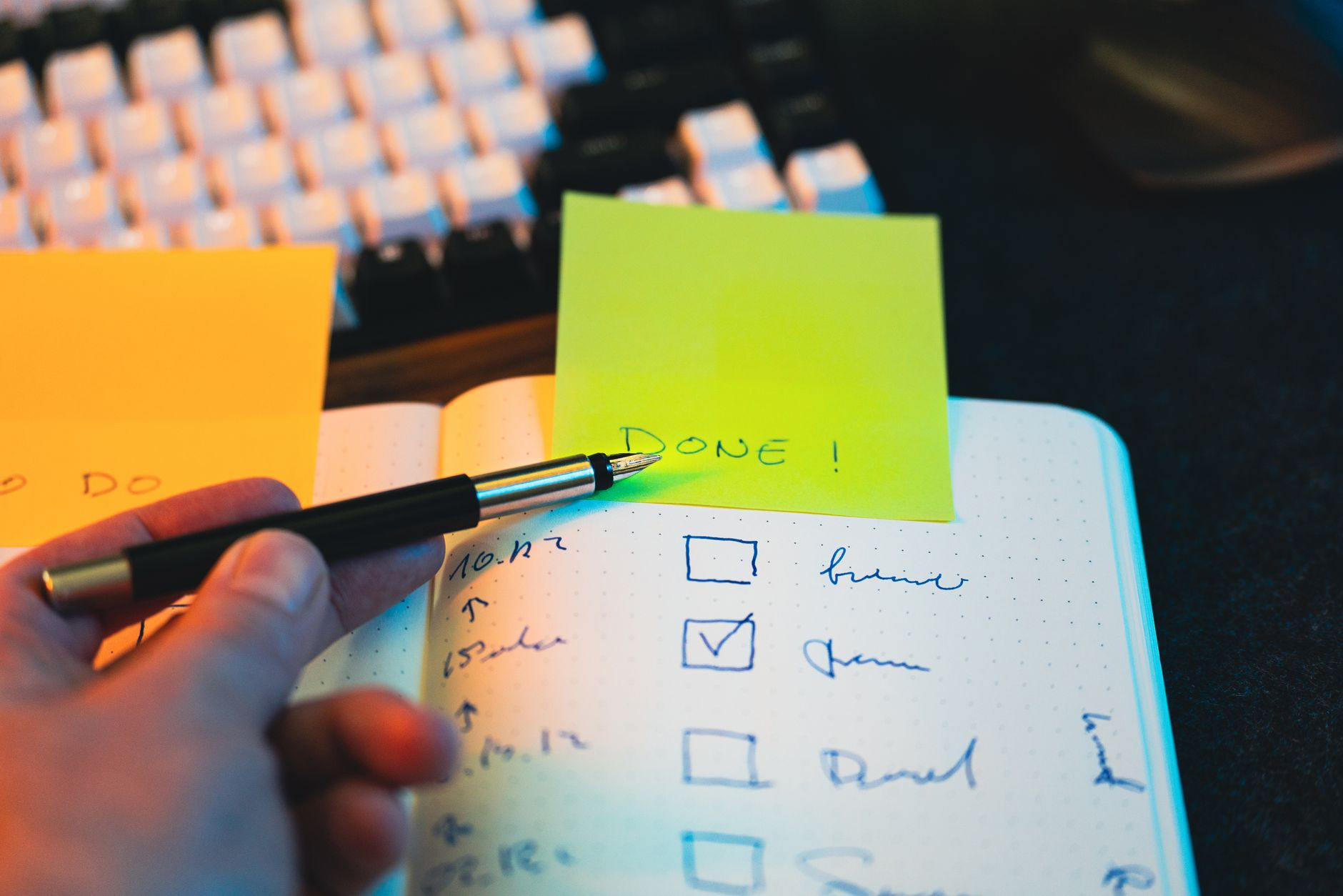 hand writing in notebook with checklist and sticky note