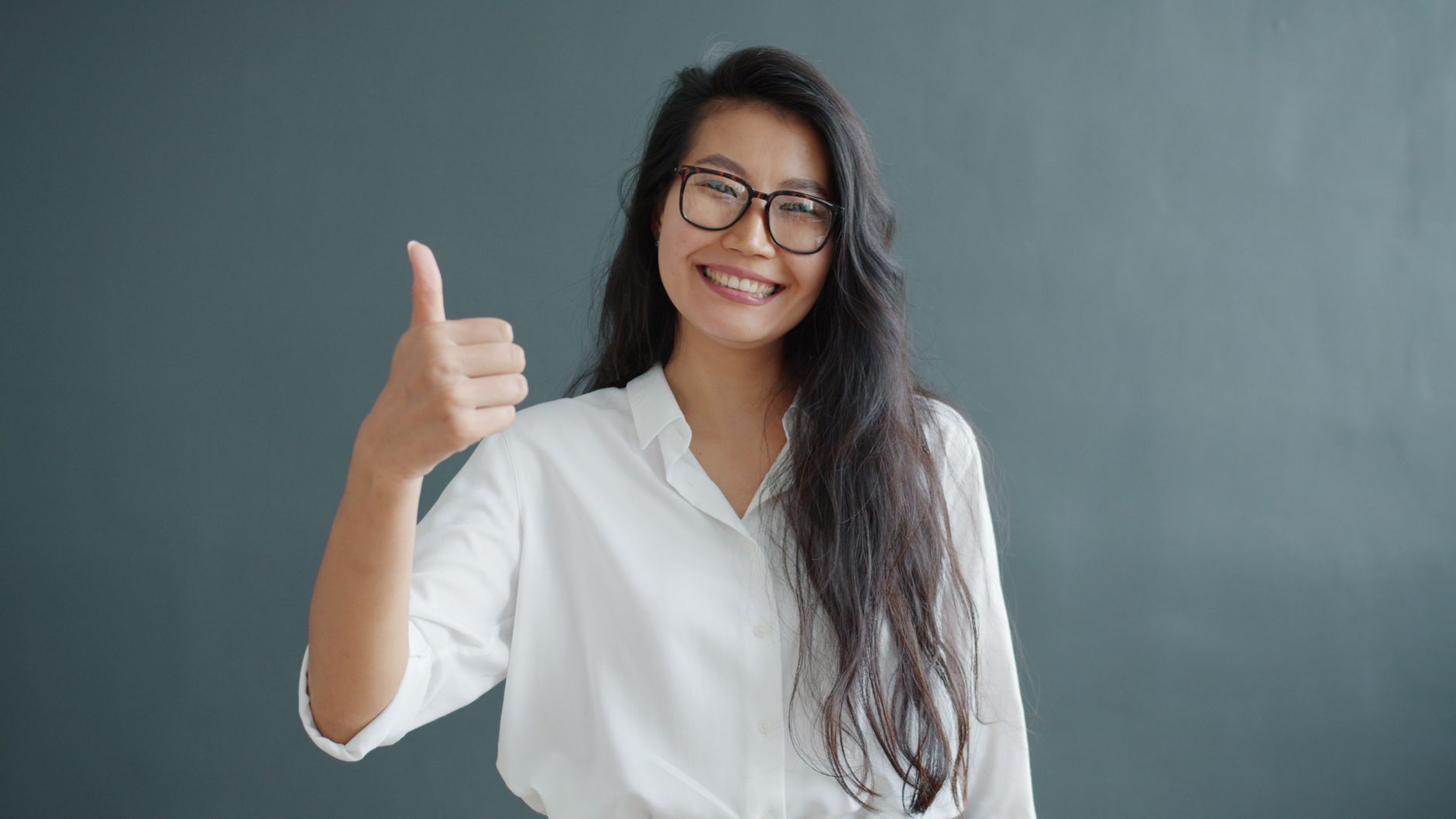 confident woman giving thumbs up in white shirt
