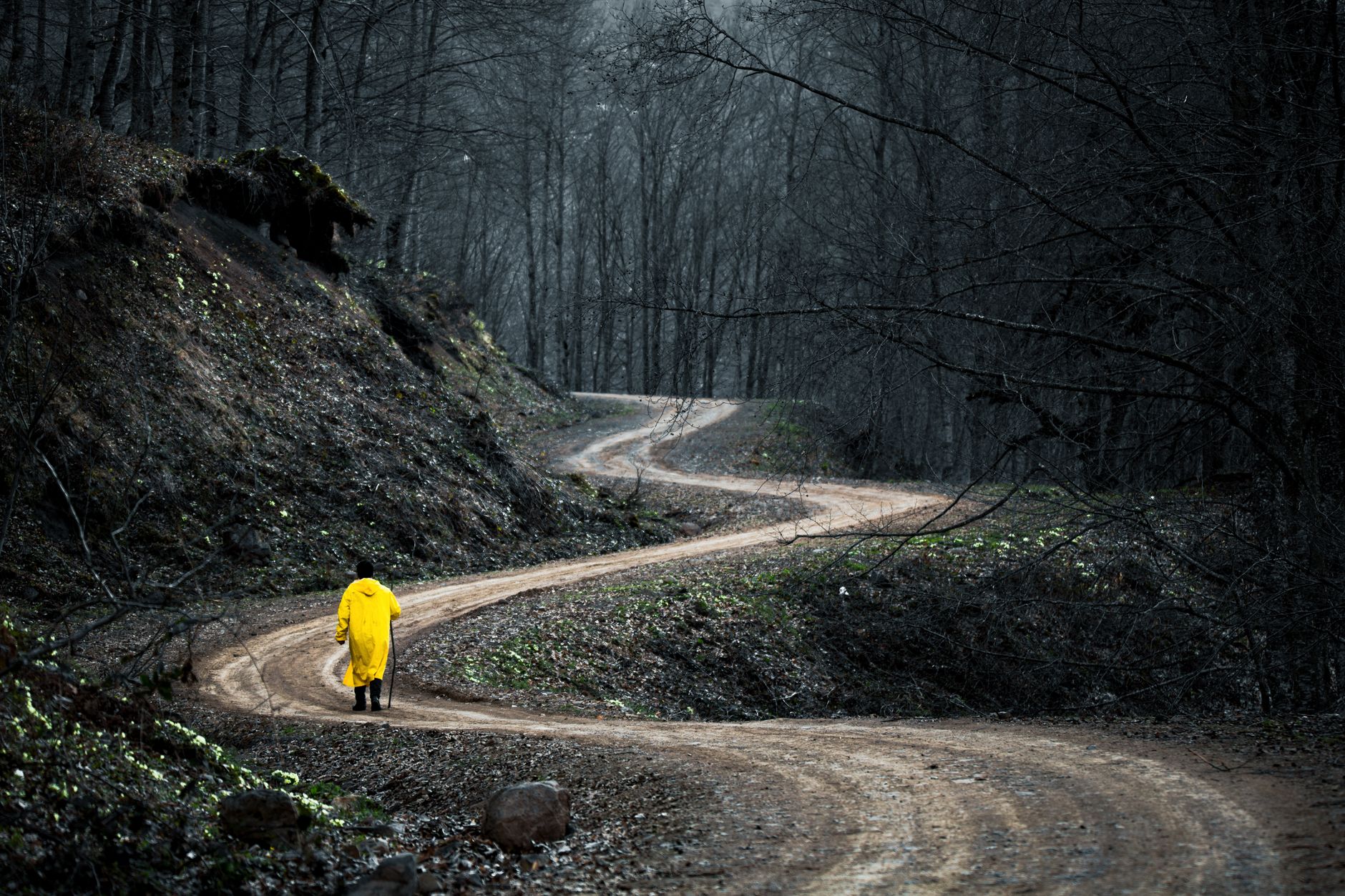 a person in yellow jacket walking on the dirt road