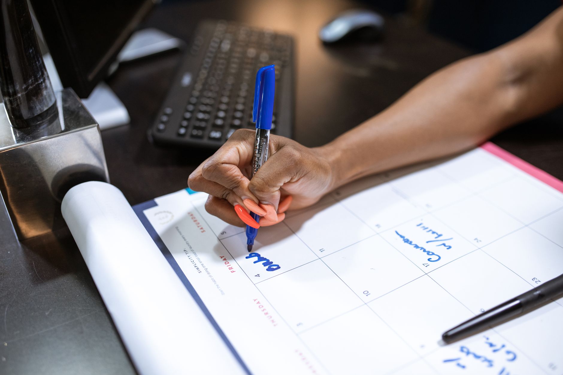 a person writing on the calendar using a blue marker