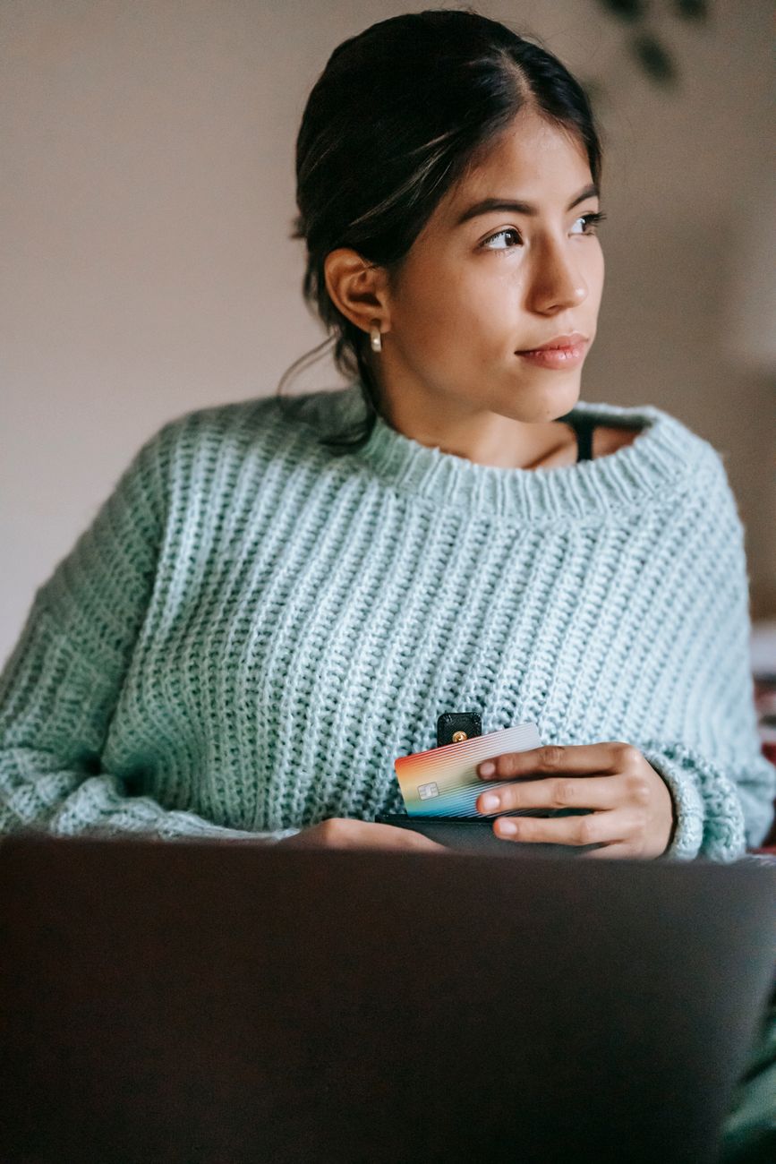 ethnic shopper with plastic card and laptop at home