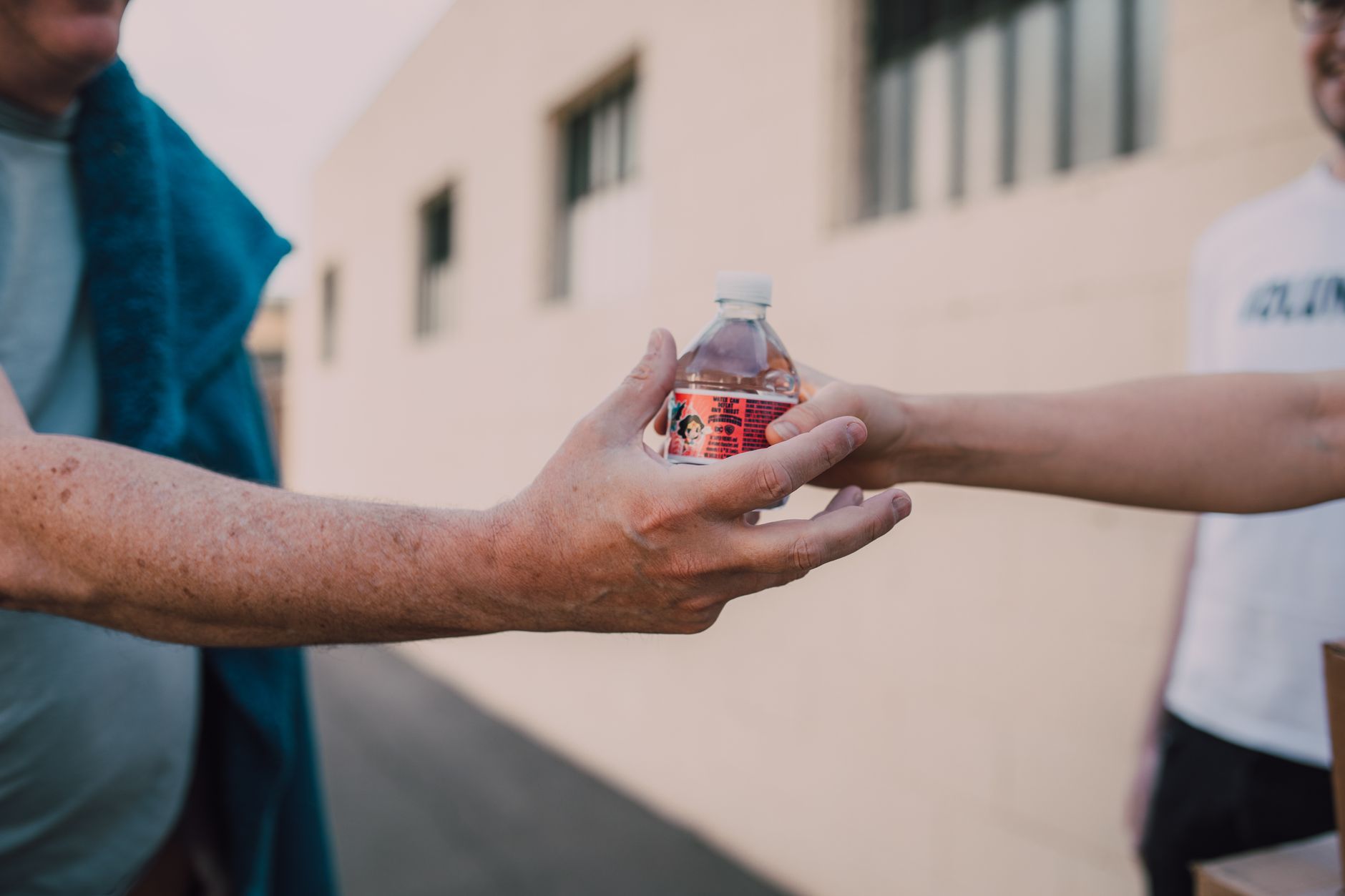 a person giving a bottled beverage to another person