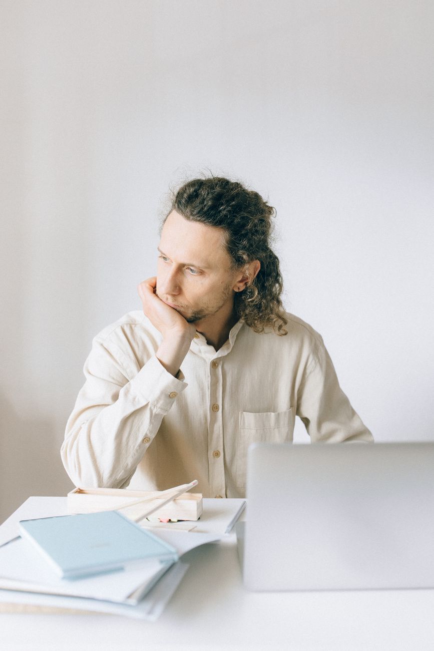 a man in white long sleeves sitting in front of a table with laptop