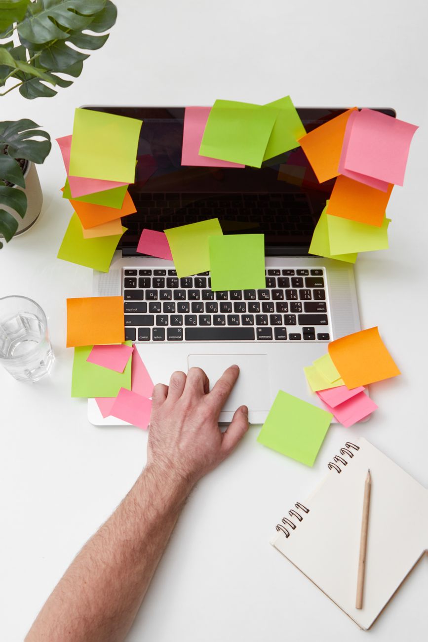 a person touching a touch pad of laptop with sticky notes