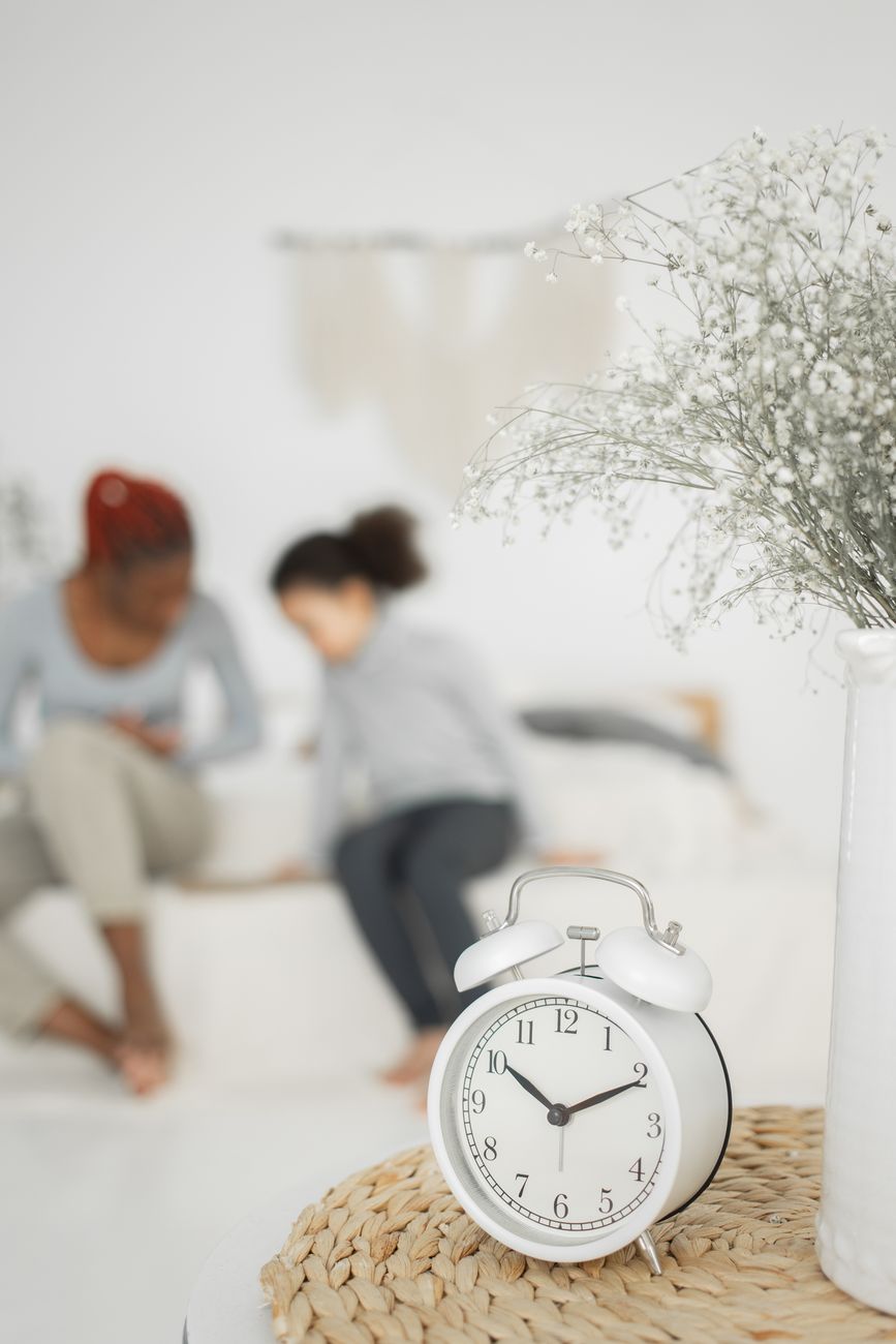 retro alarm clock placed on table near anonymous black woman and child