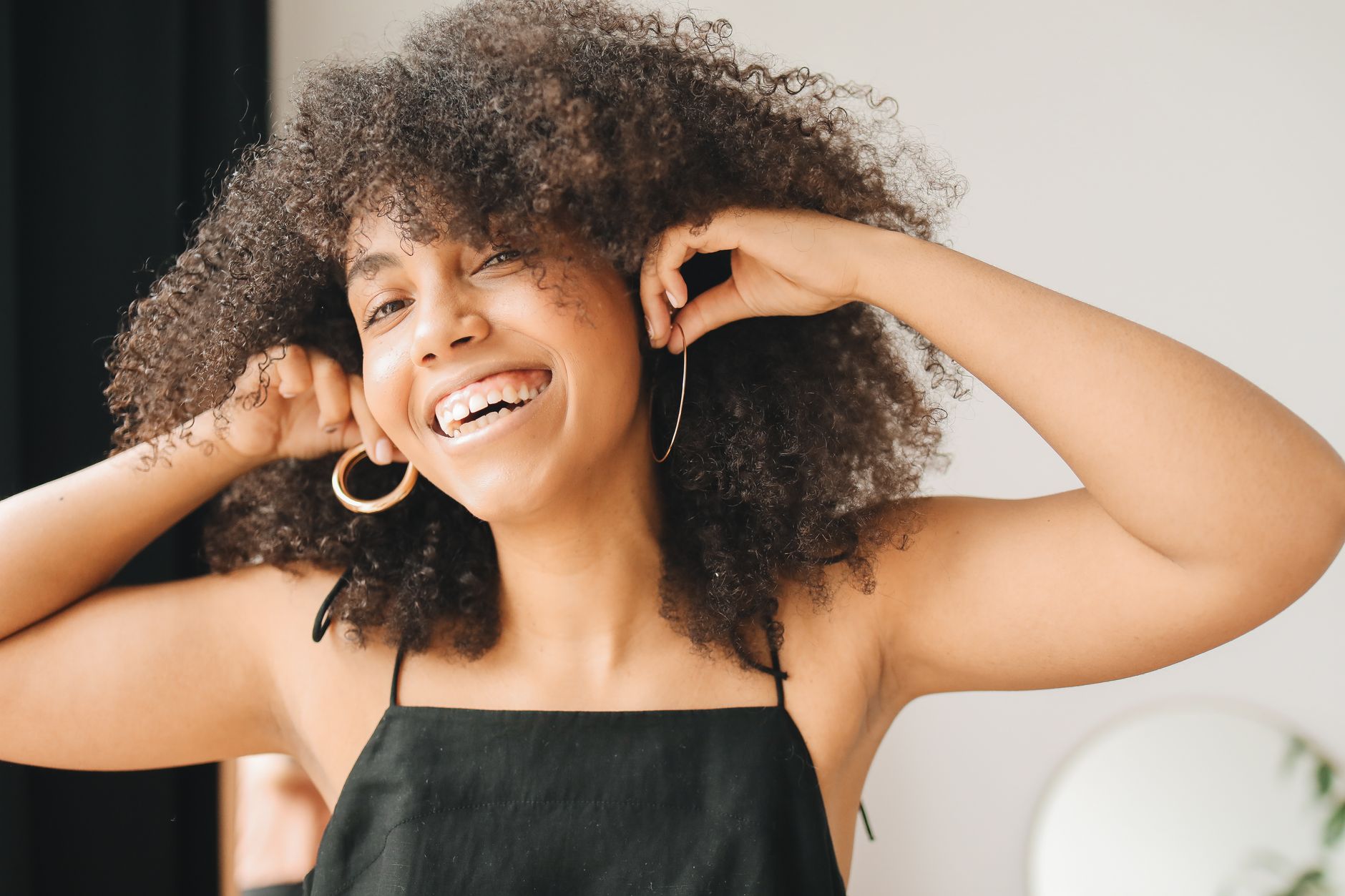 woman in black dress trying gold earrings