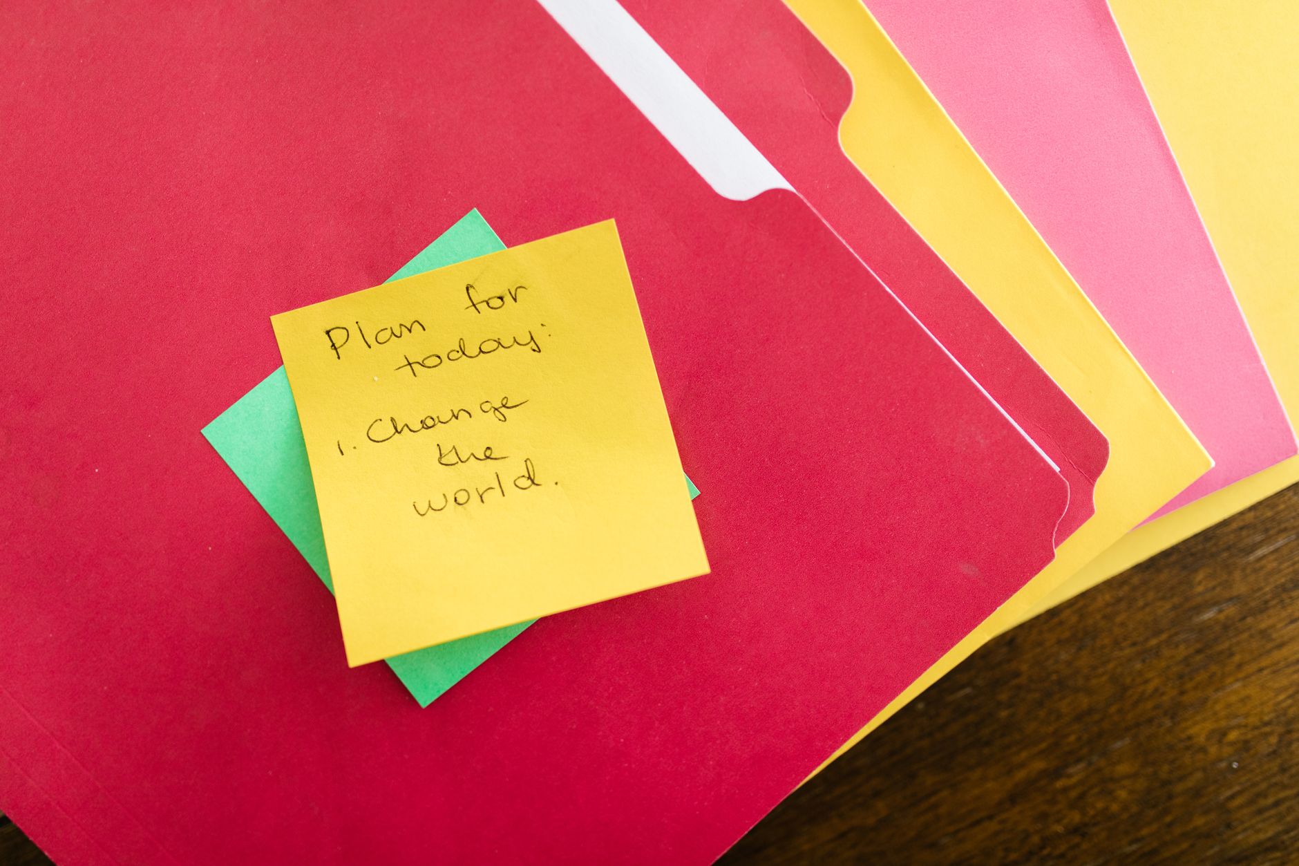 a message written on a yellow post it note on top of folders