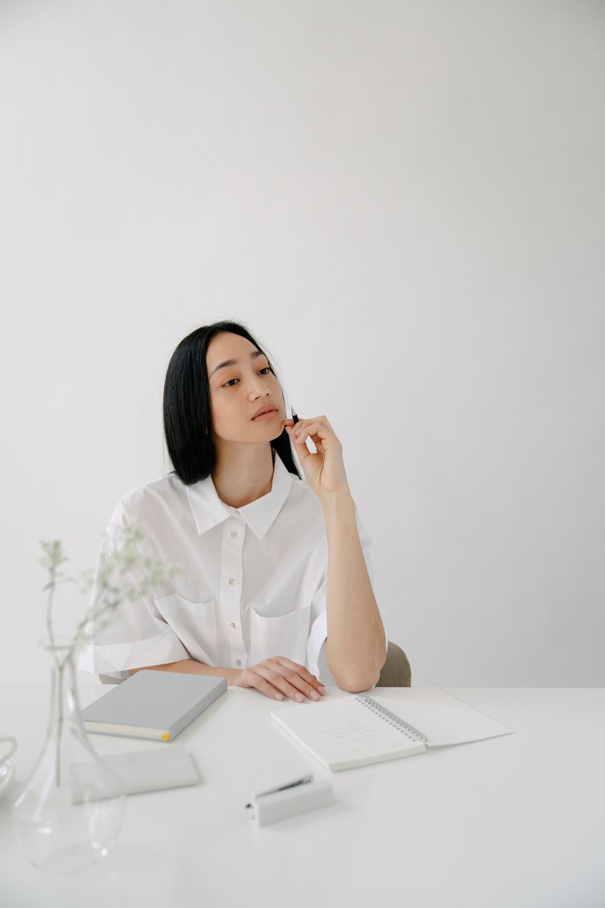 thoughtful asian employee with agendas at office table