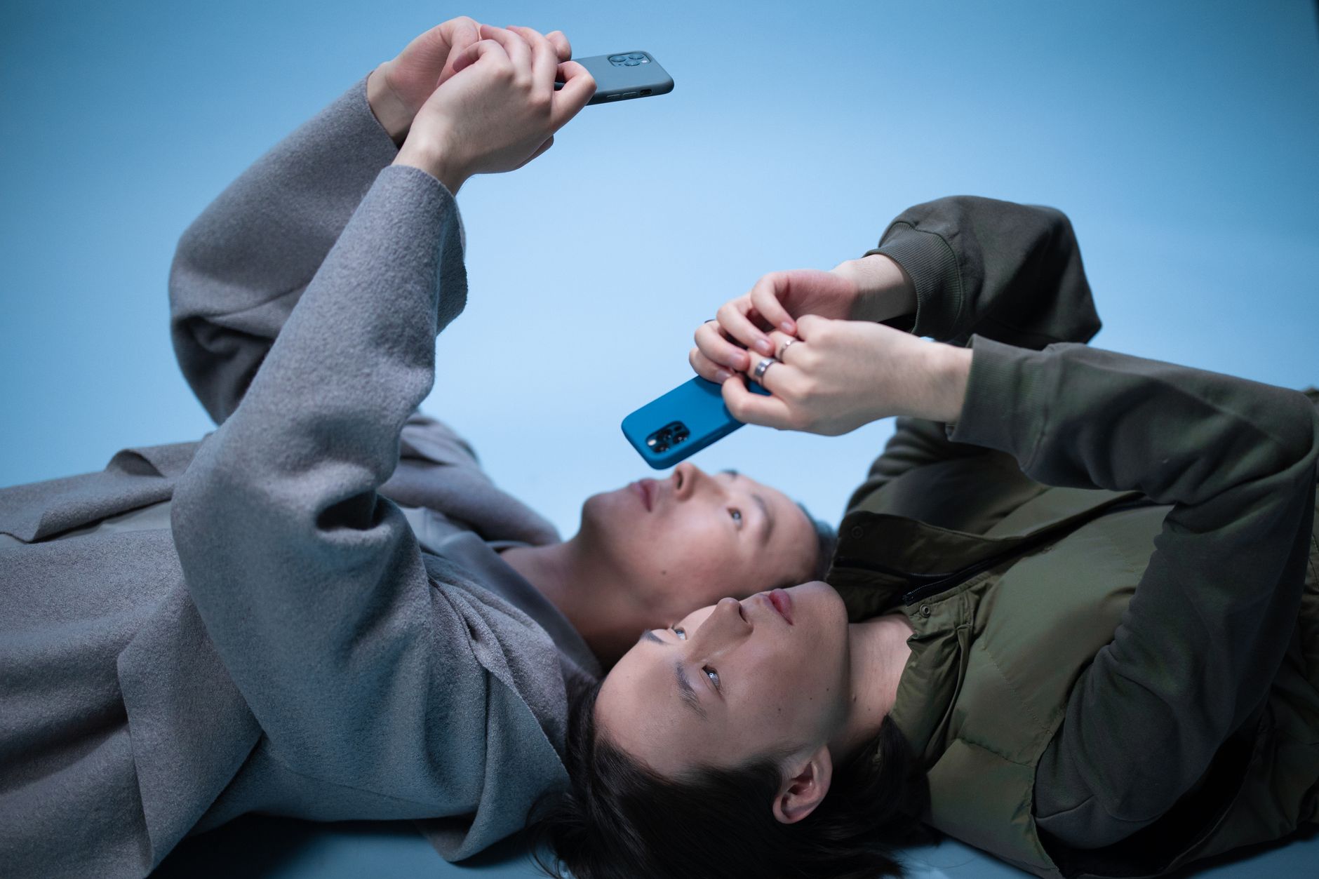 twins lying on the floor while using cellphones