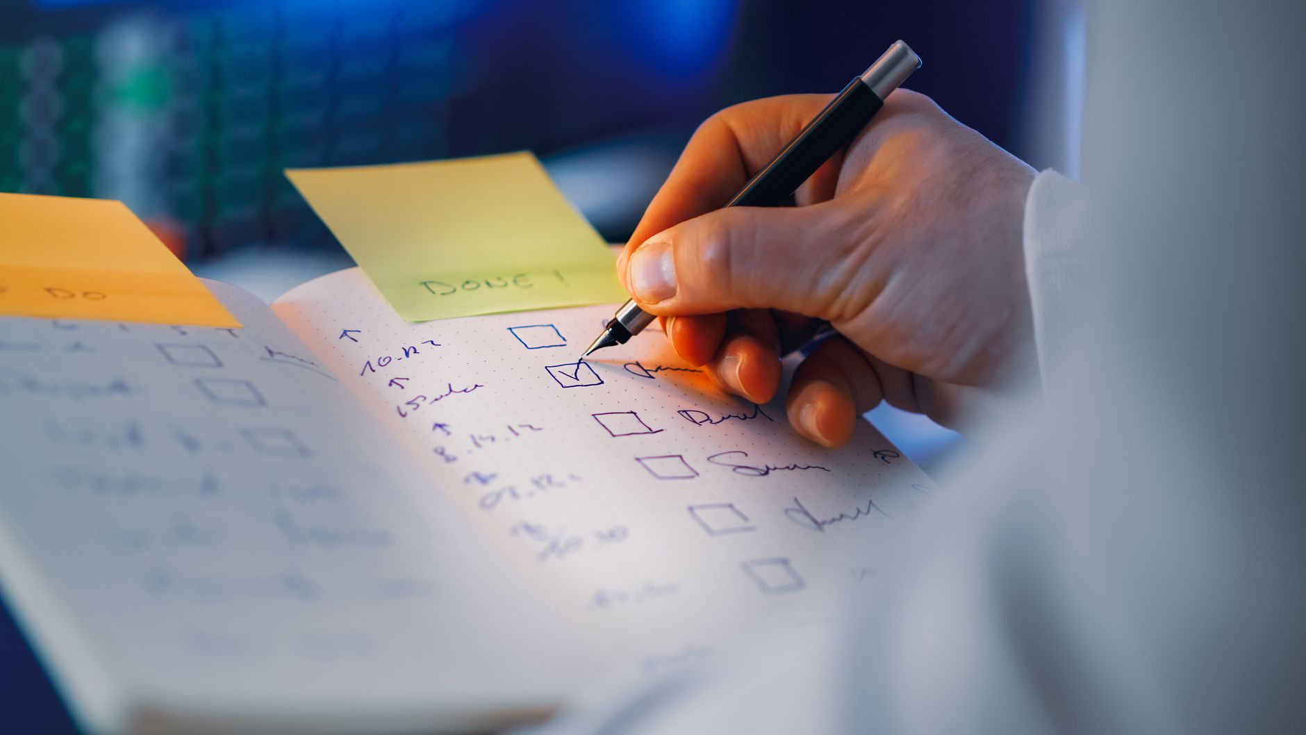 hand writing in notebook with checklist in focus