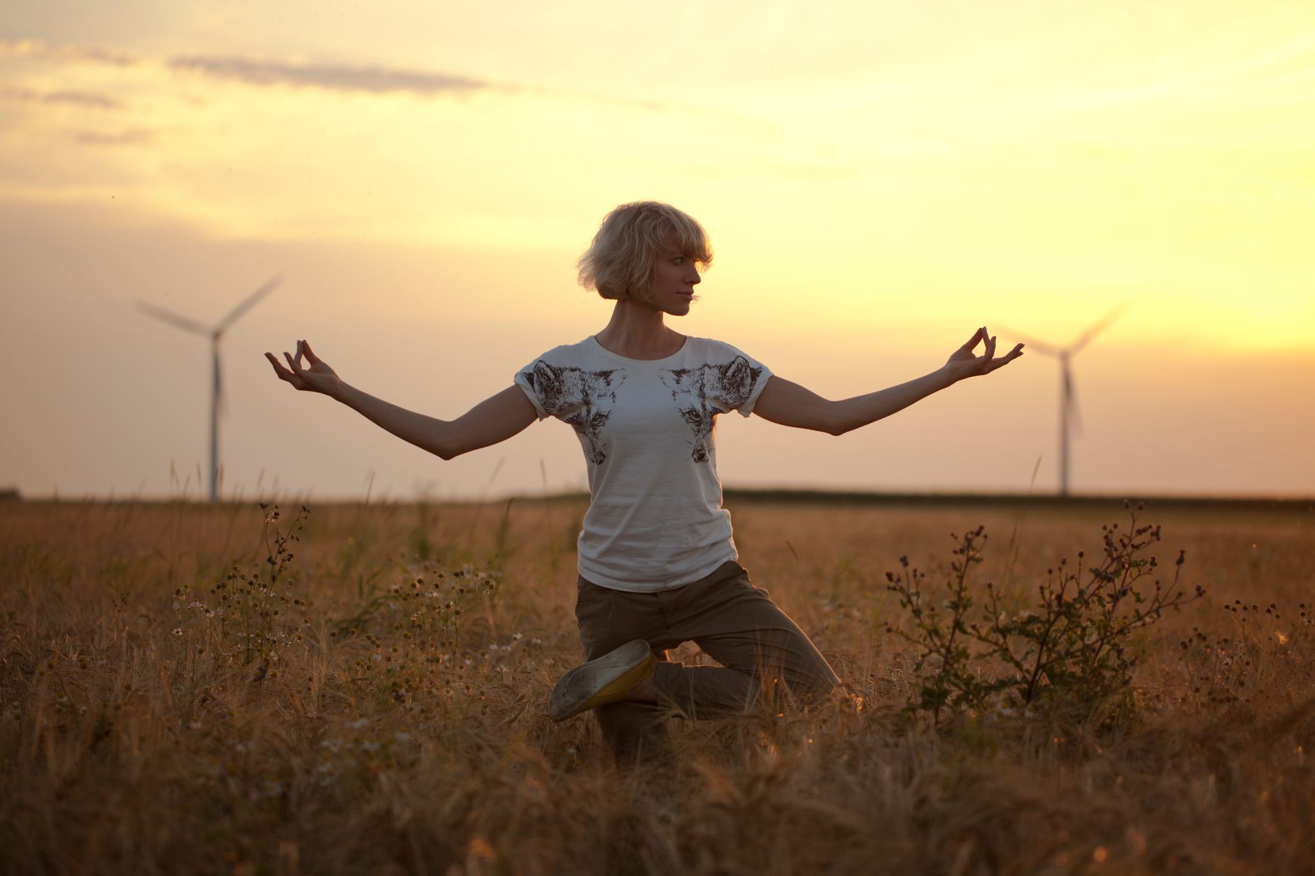 woman doing yoga pose in brown grass field