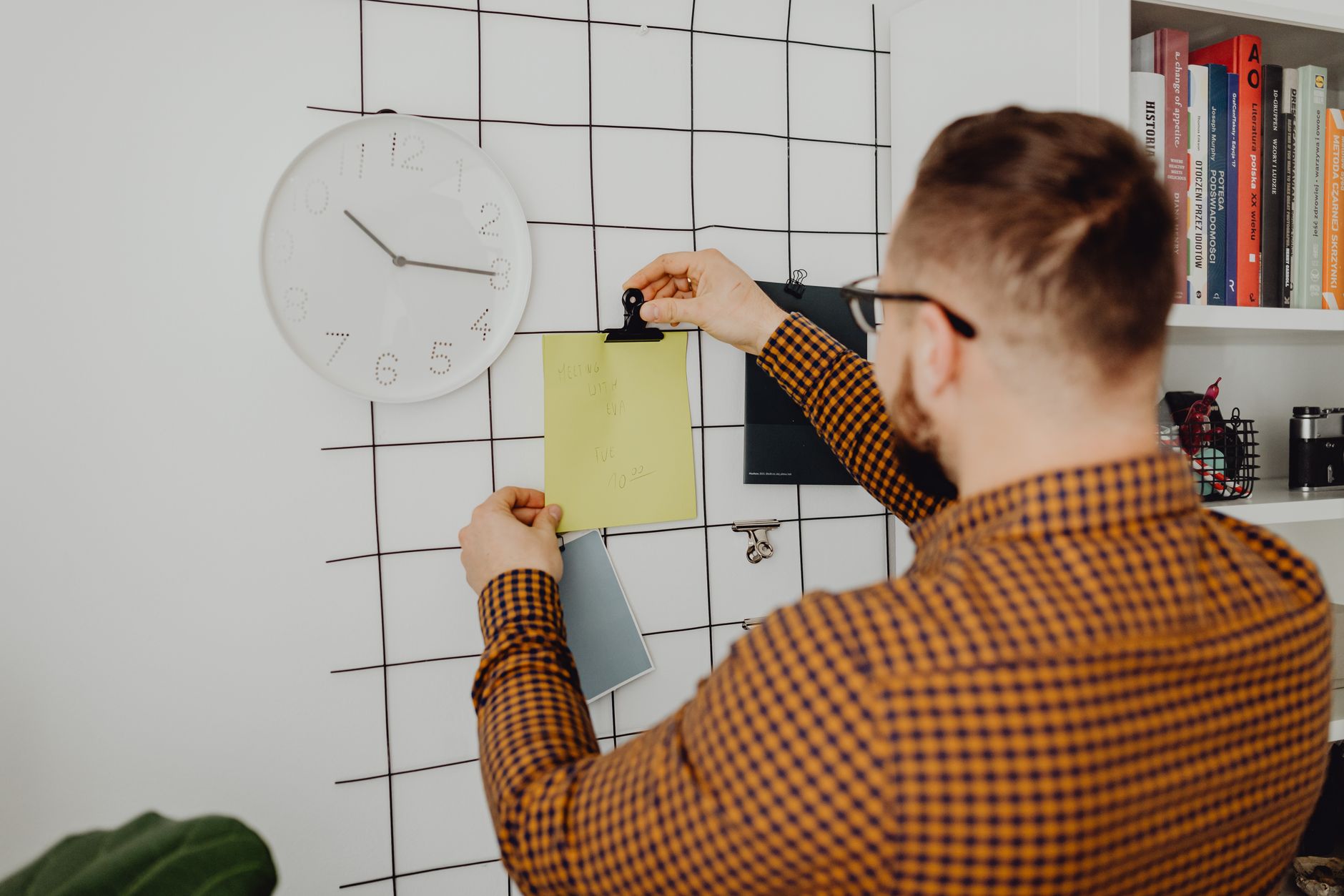 a man clipping a schedule on the wall grid