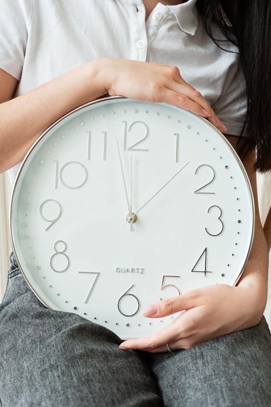 a person in white polo shirt holding a clock